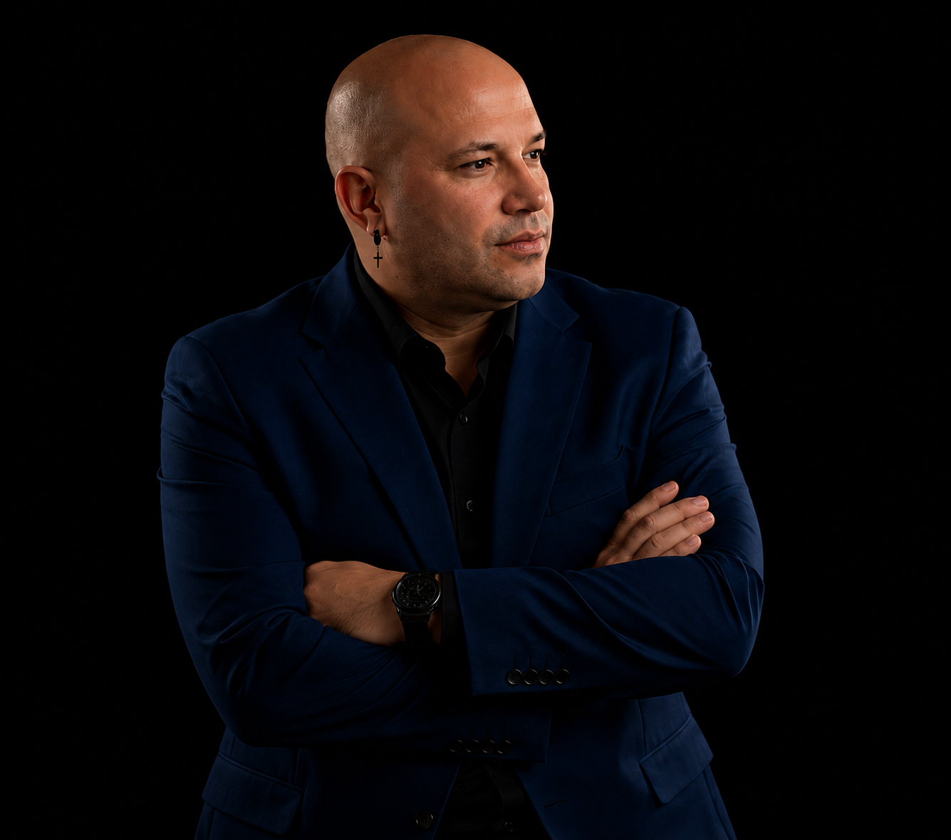 Carlos Quintín de pie, brazos cruzados, sobre fondo negro
